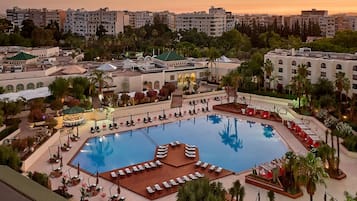 Relax by the resort's central pool surrounded by lush gardens and palm trees.