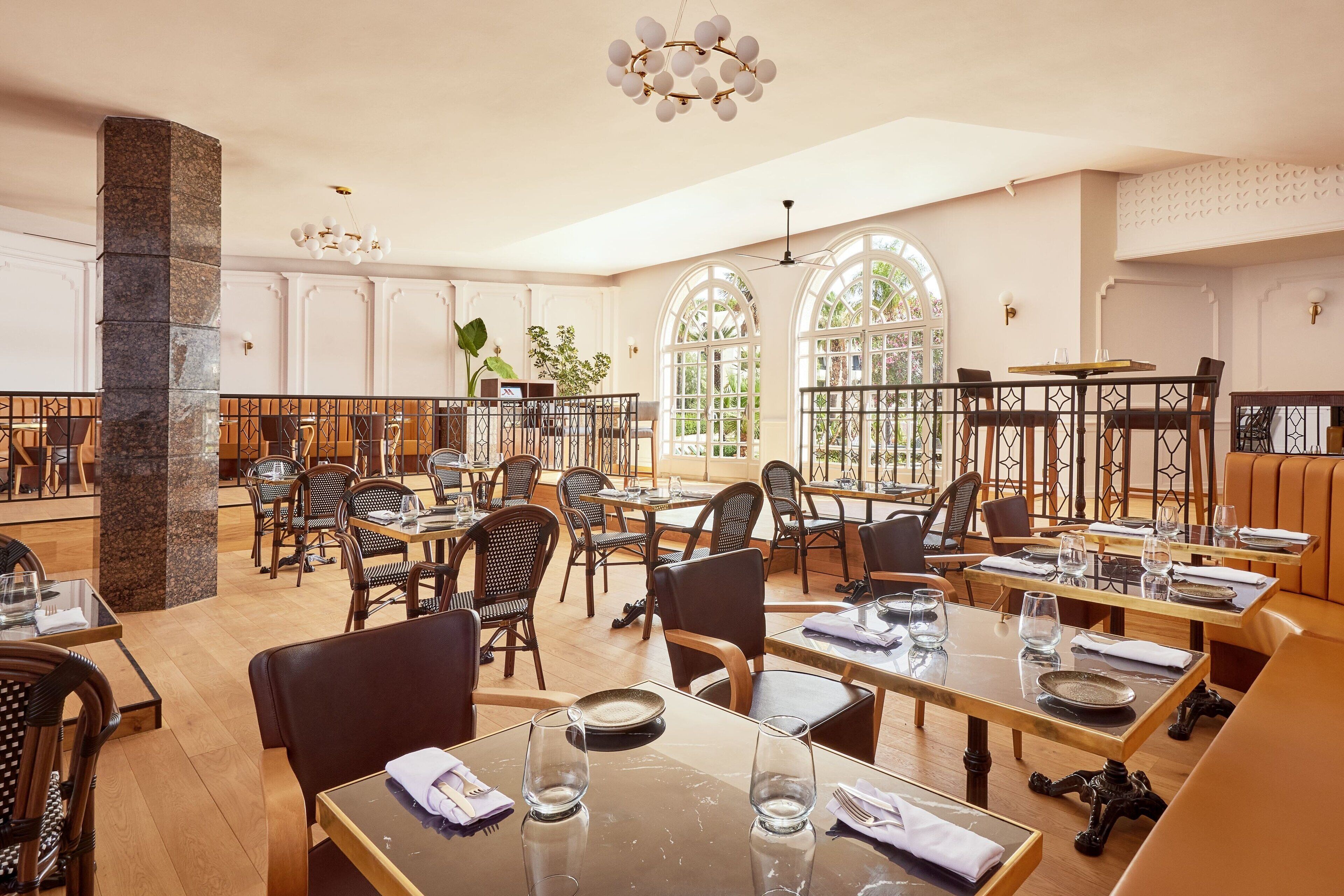 Ein geräumiges Restaurant mit hohen Decken, großen Fenstern und unterschiedlichen Sitzmöglichkeiten, darunter Tische und Stühle.