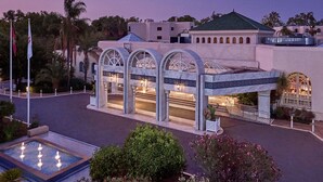 Entrada de hotel con una fuente, columnas en arco y piscina.