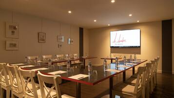 A conference room with a long table, white chairs, water bottles, and a presentation screen displaying 'Le Londres'.