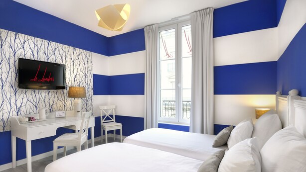 A hotel room with two beds, a desk, a TV, and a window with curtains.