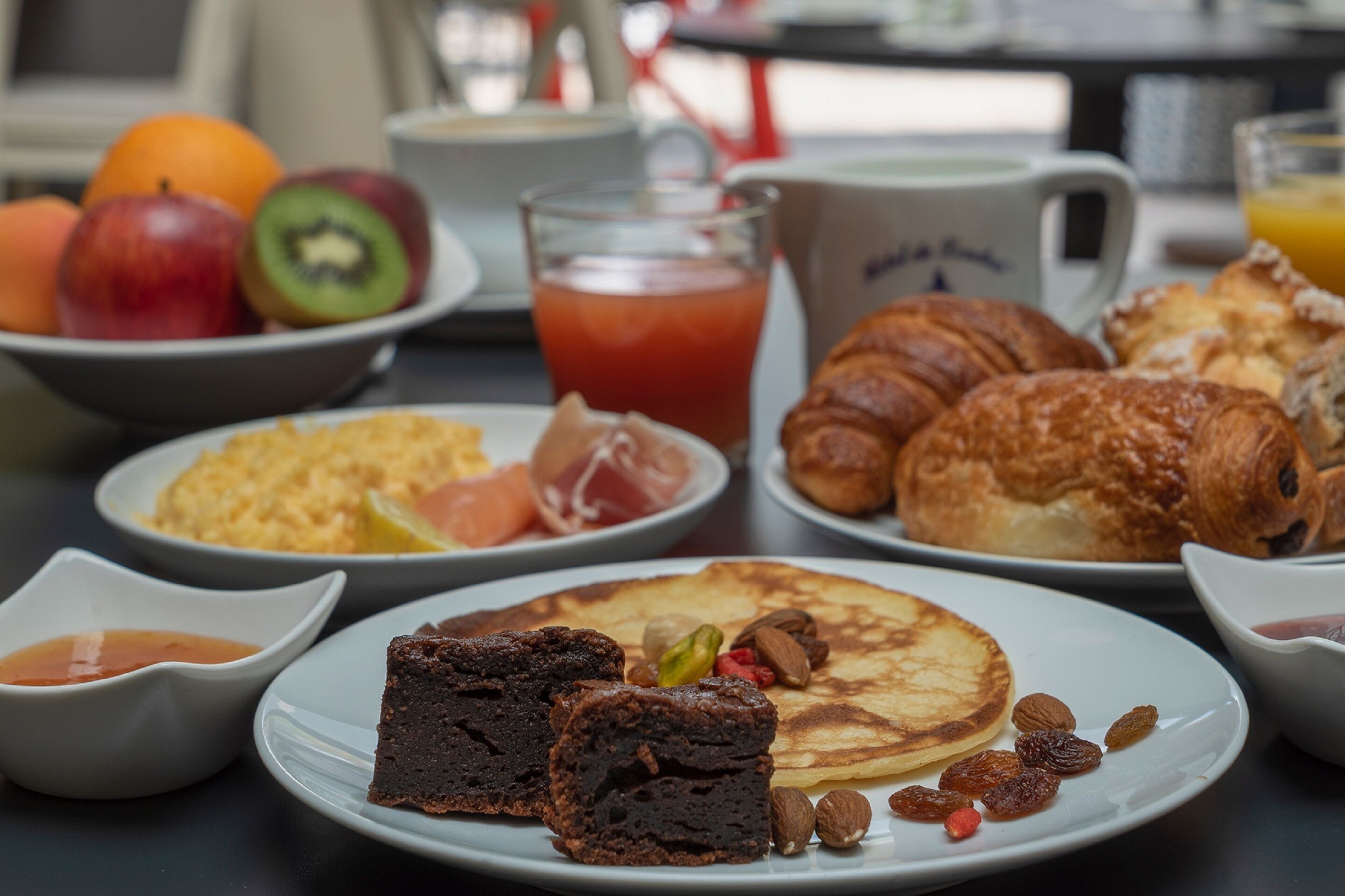 A breakfast table with various food items including pancakes, croissants, and a slice of pie.