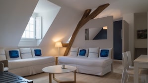 A modern, well-lit room with a high ceiling, white furniture, and a visible skylight.