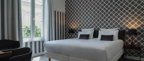 A modern bedroom with a large bed, a desk, and a chair.