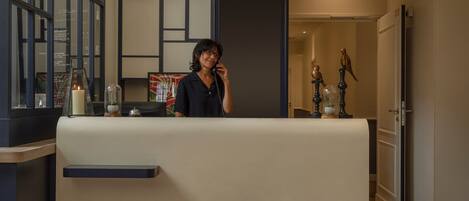A reception area with a counter, a person standing behind it, and decorative items including a candle and figurines.