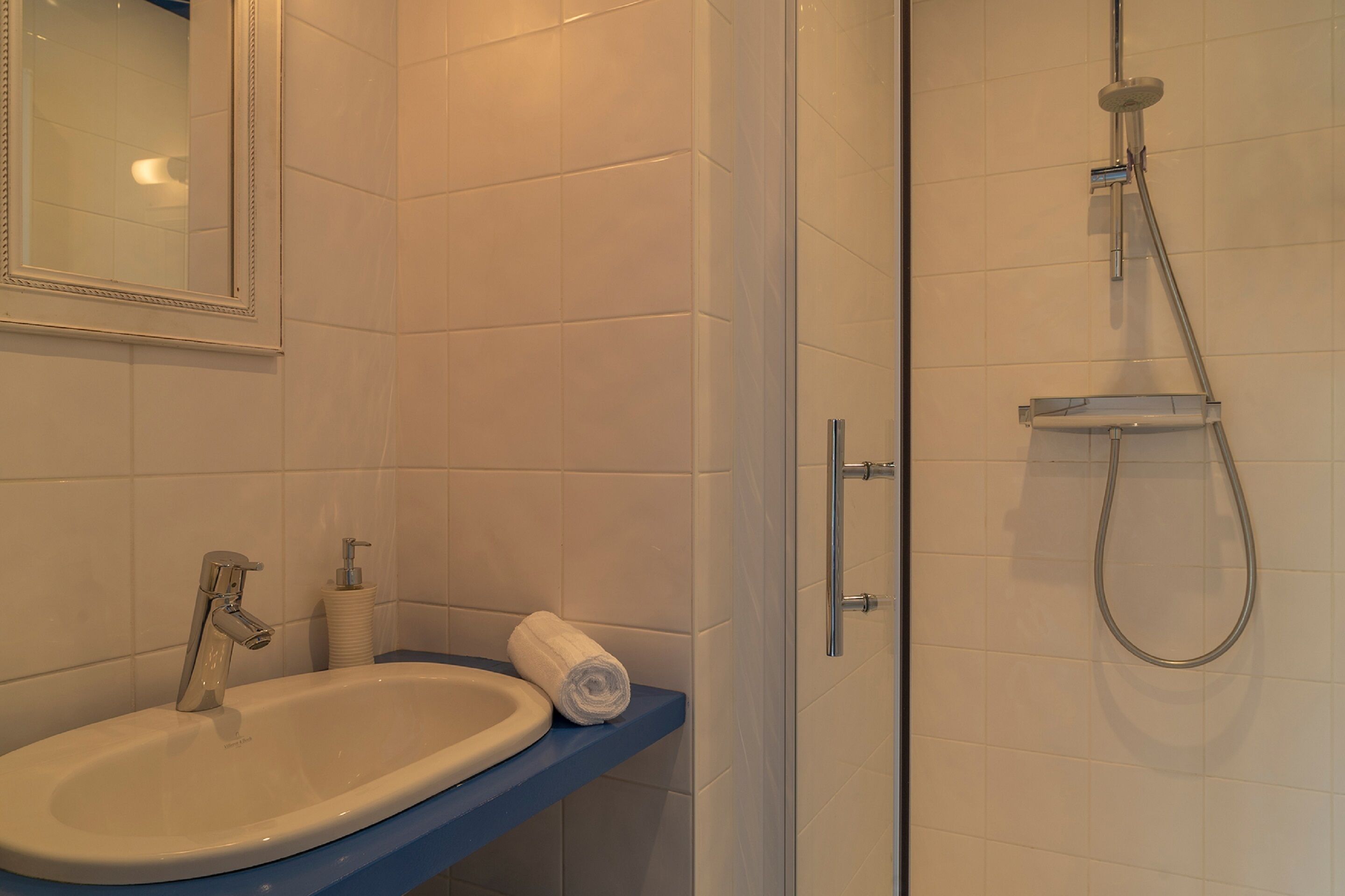 A bathroom with a sink, mirror, and shower.