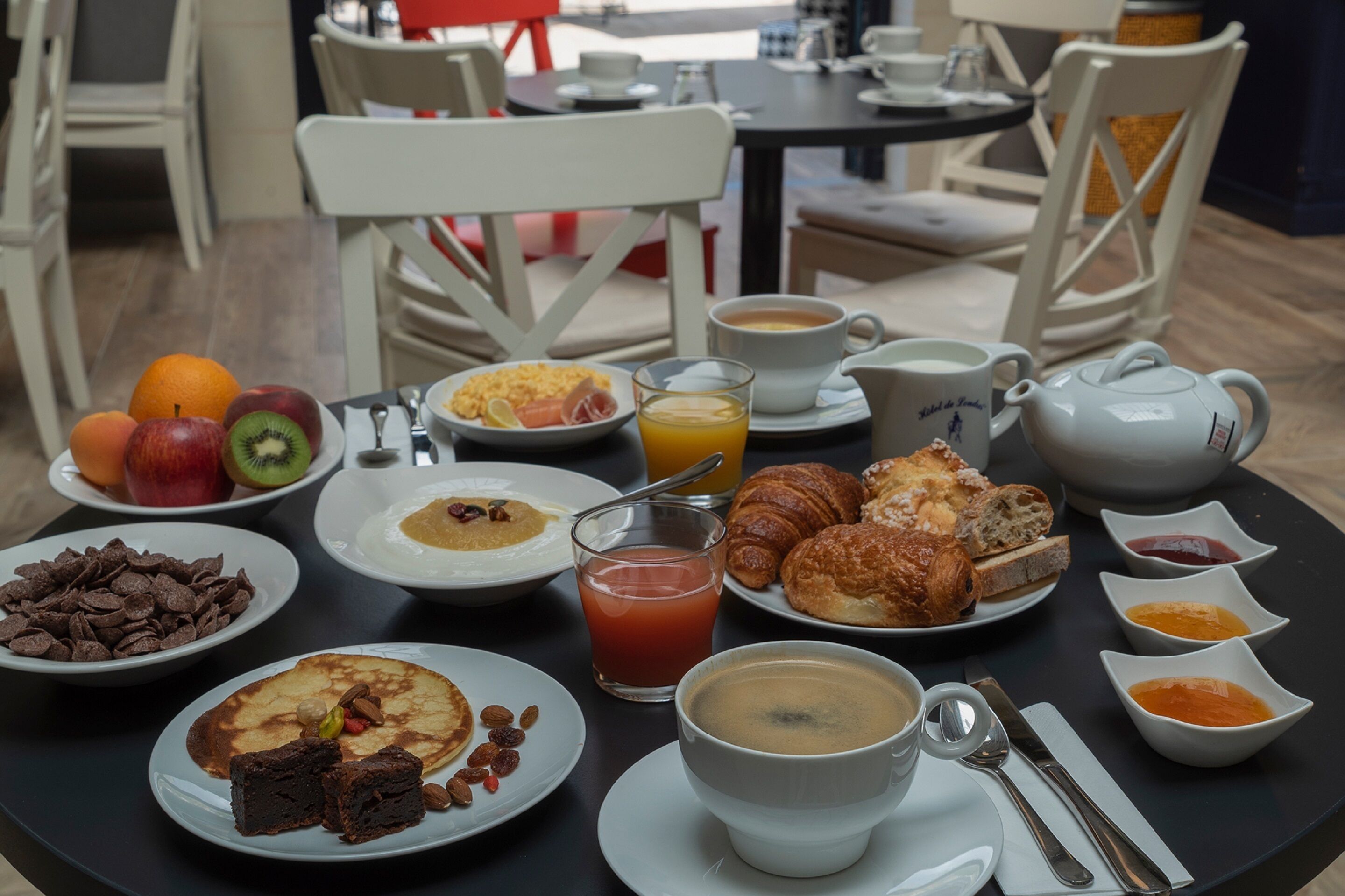 A breakfast table with various dishes including fruits, pastries, and beverages.