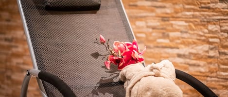 Una silla reclinable con respaldo de malla, un cojín y un pequeño ramo de flores.
