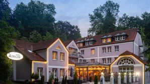 A hotel with a well-lit entrance, multiple windows, and a covered outdoor seating area.