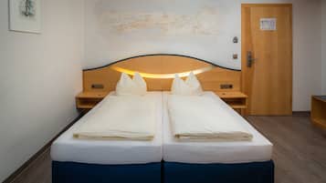 Ein Doppelbett mit Holzkopf, zwei Nachttische und eine Wandkarte.