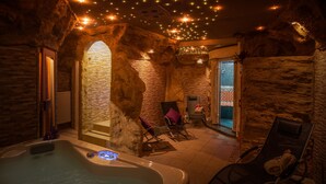 A spa area with a hot tub, seating, and a stone wall.