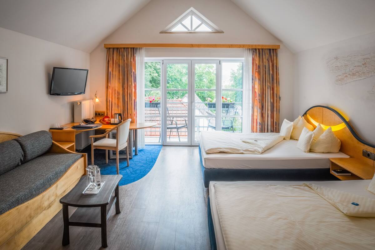 A hotel room with a loft bed, a sofa, a desk, and a television.