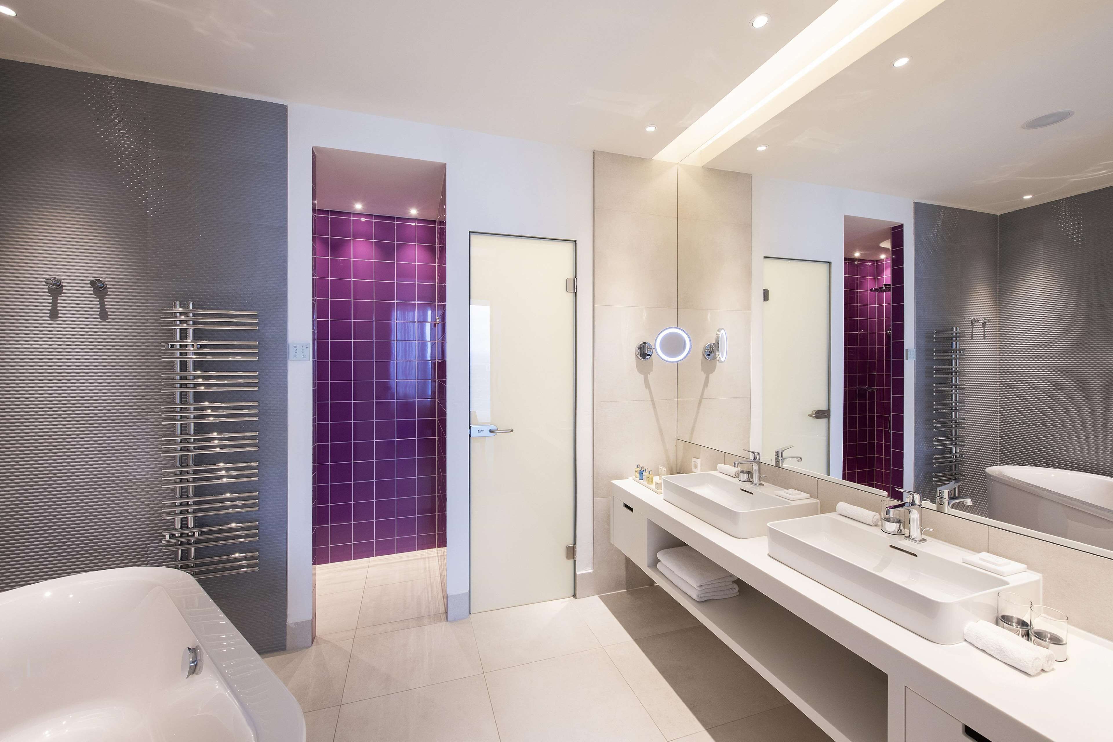 A modern bathroom with a large bathtub, two sinks, and a mirror.