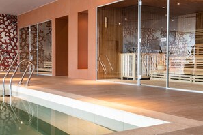 A modern indoor pool area with glass walls, wooden flooring, and a clear view of the pool.