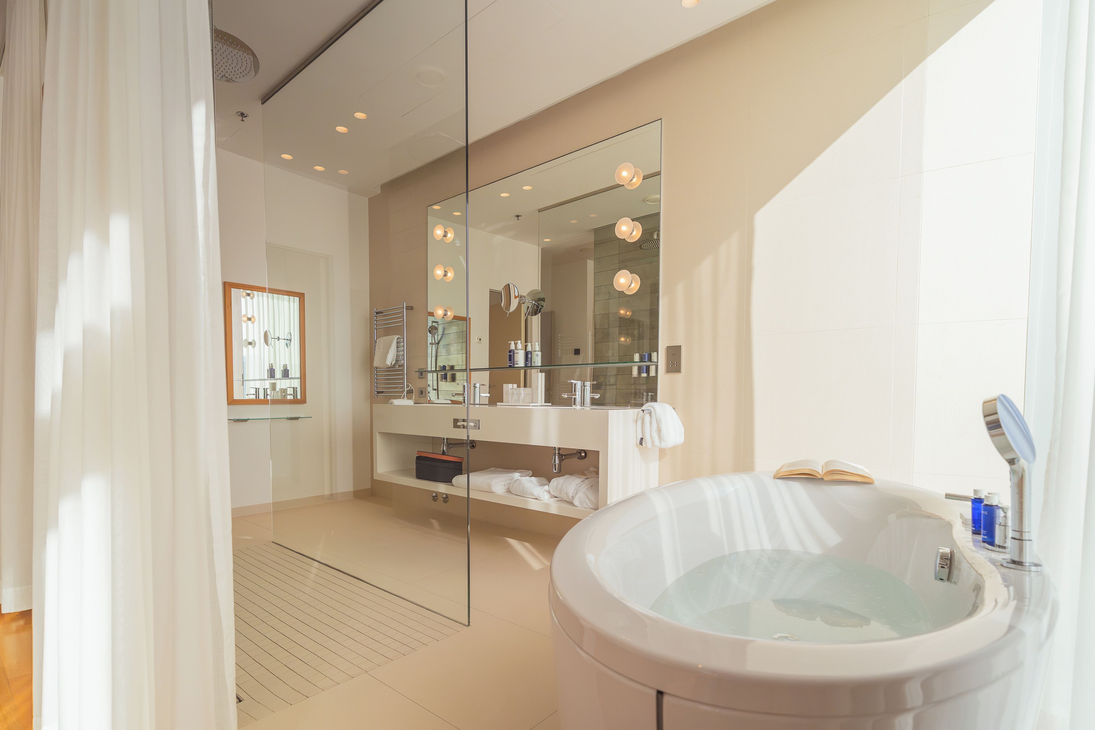 Une salle de bain moderne dotée d’une grande baignoire, d’une douche à parois de verre et d’un meuble-lavabo avec un miroir.