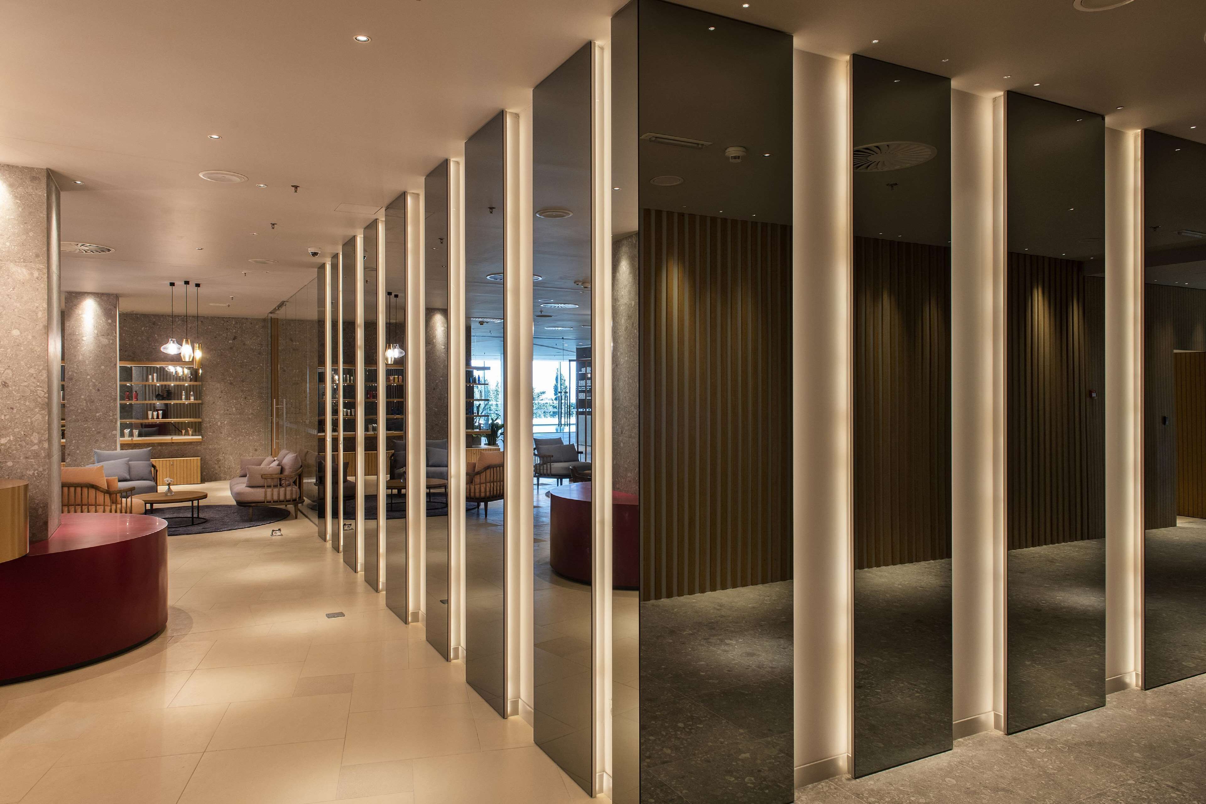 Eine moderne Hotellobby mit einer Rezeption, einer Sitzecke und Blick in den Speisesaal.