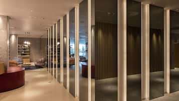 Un moderno vestíbulo de hotel con una recepción, un área de descanso y vistas al comedor.