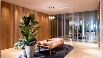 Eine moderne Lobby mit einer Lounge, ausgestattet mit einer Couch, Topfpflanzen und einer Glastrennwand.