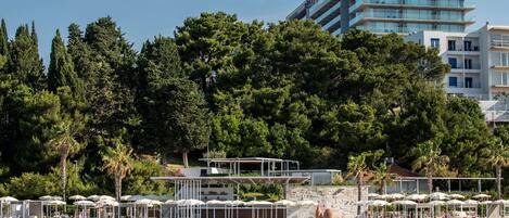 Ein Hotel an der Küste mit Poolbereich, Sitzgelegenheiten im Freien und Meerblick.