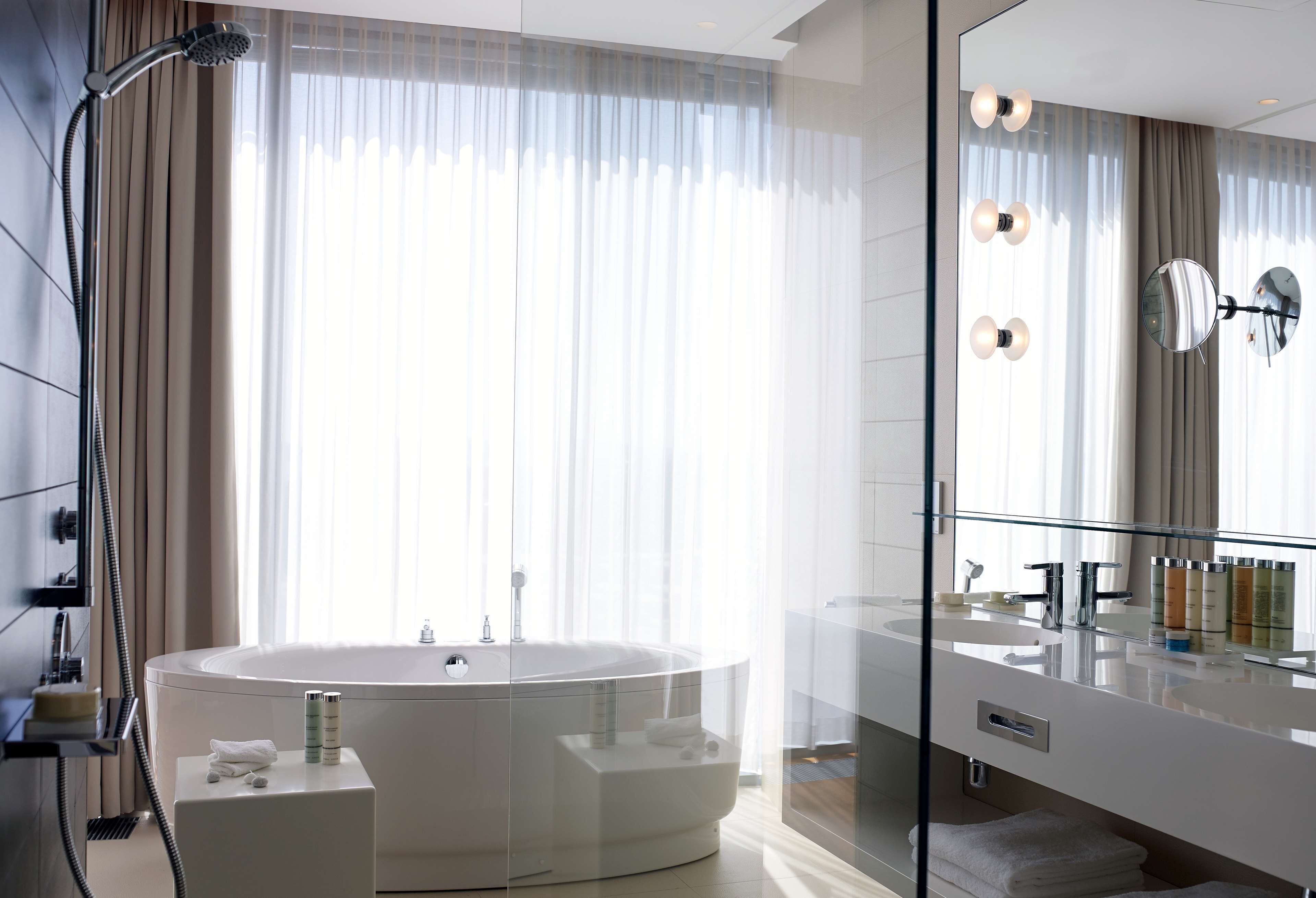 A modern bathroom with a freestanding bathtub, a glass-enclosed shower, and a large mirror.