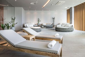 A modern spa area with lounge chairs, a seating area, and potted plants.