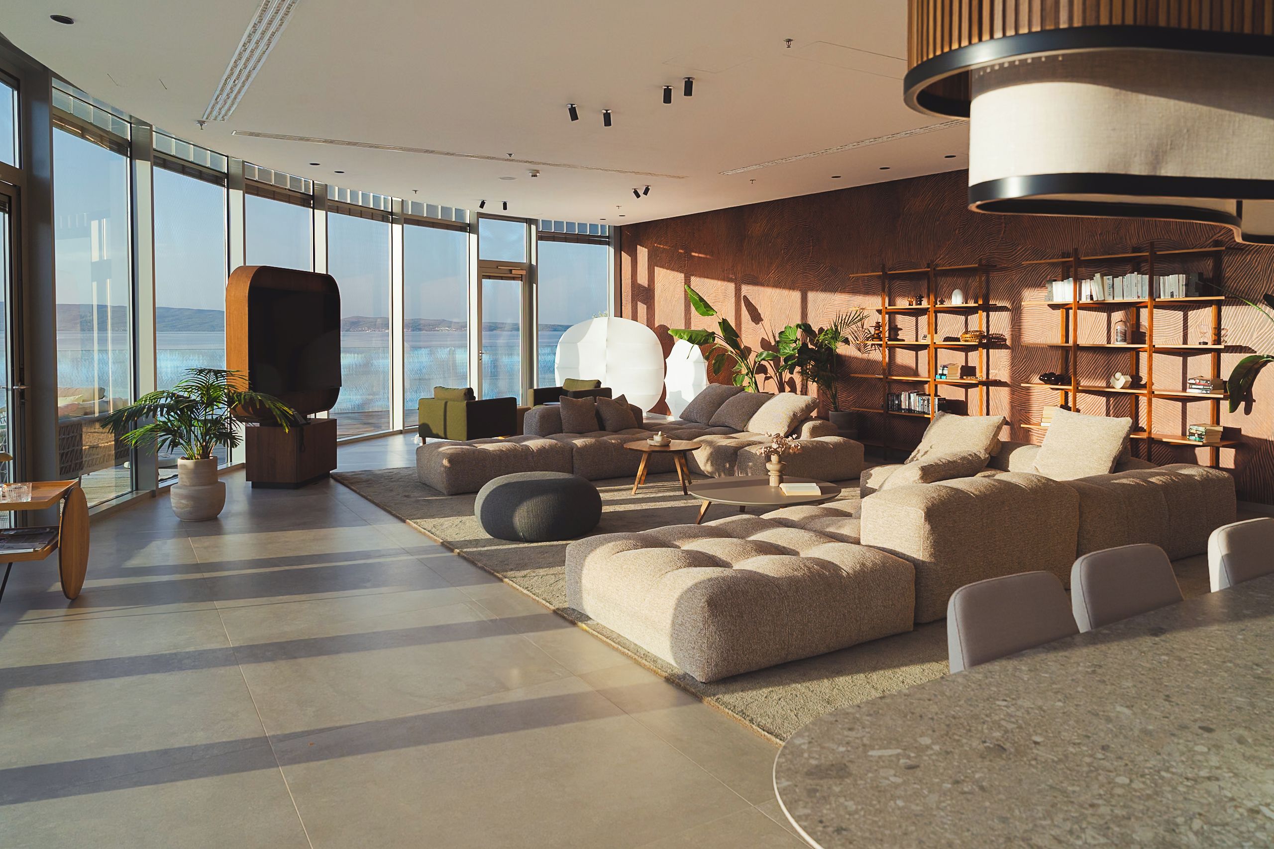 A spacious living area with a large sofa set, a coffee table, and a bookshelf.