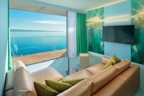 Relax in comfort with a sofa, flat-screen TV, and ocean views through a large window.