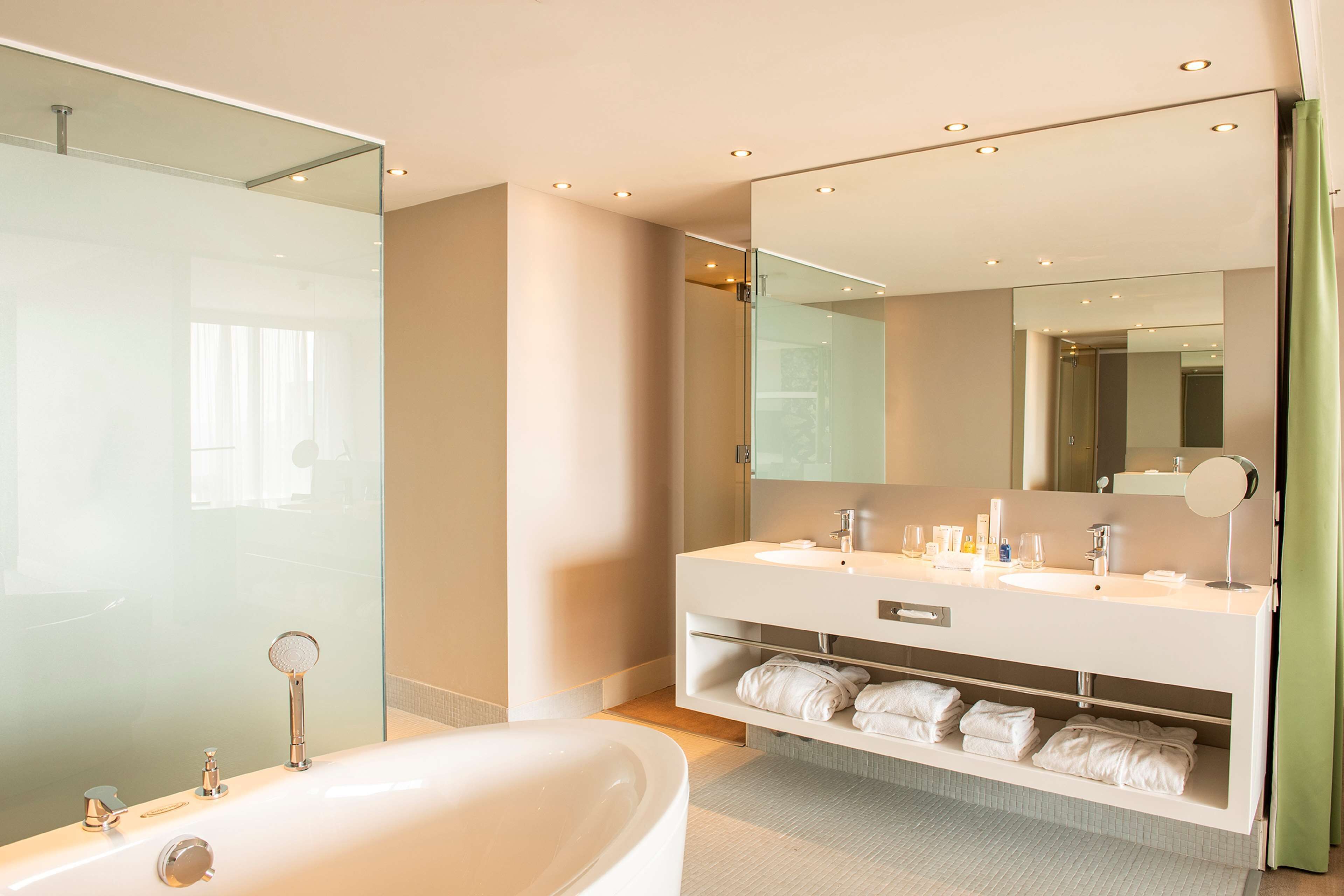 Une salle de bain moderne avec une grande baignoire, une douche à parois de verre et un meuble-lavabo avec un miroir.