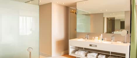 Un baño moderno con una bañera grande, una ducha con mampara de cristal y un tocador con espejo.