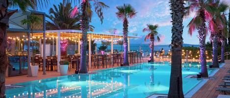 A poolside area with a bar, seating, and palm trees.