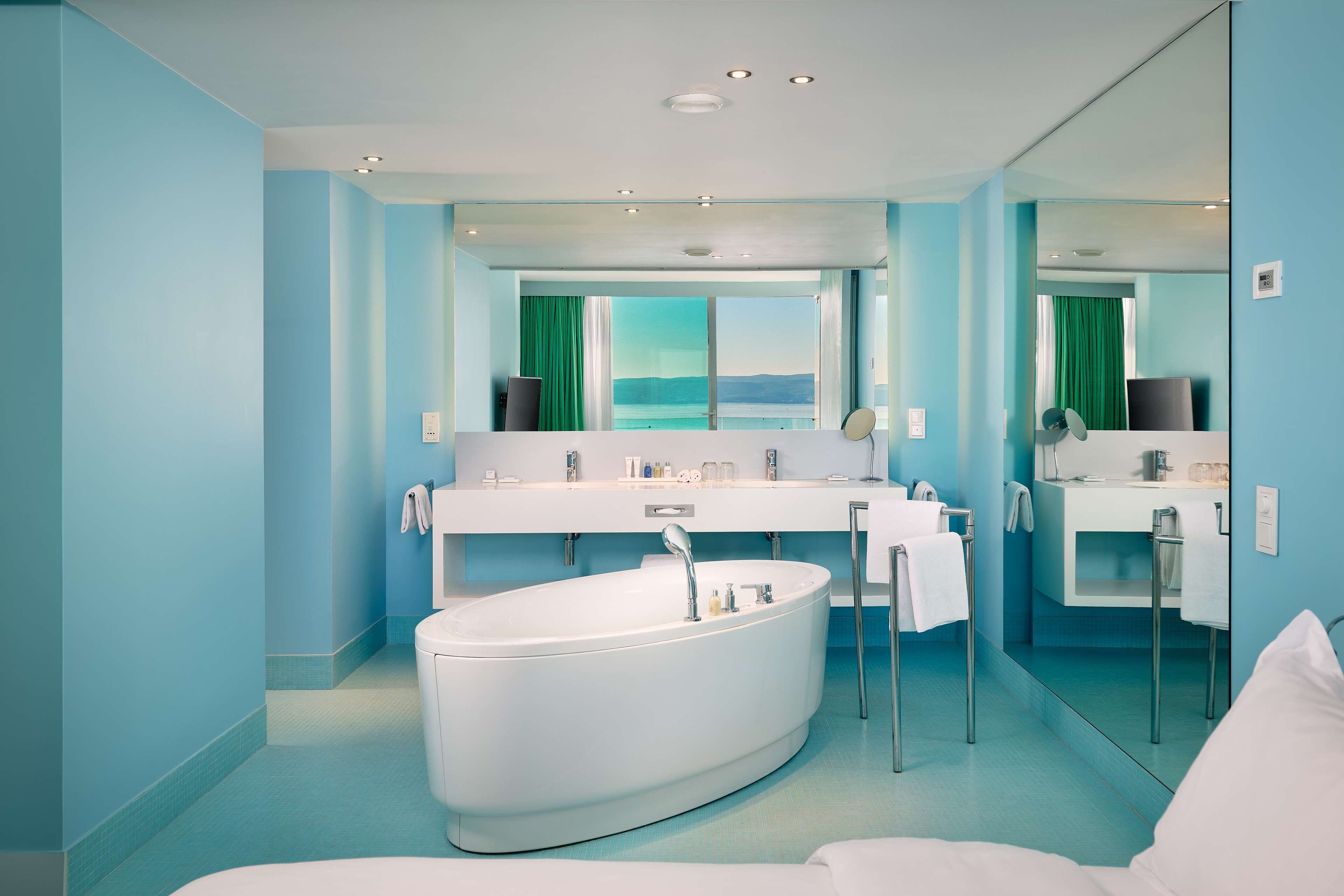 A modern bathroom with a large bathtub, a double sink vanity, and a large mirror.