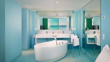 A modern bathroom with a large bathtub, a double sink vanity, and a large mirror.