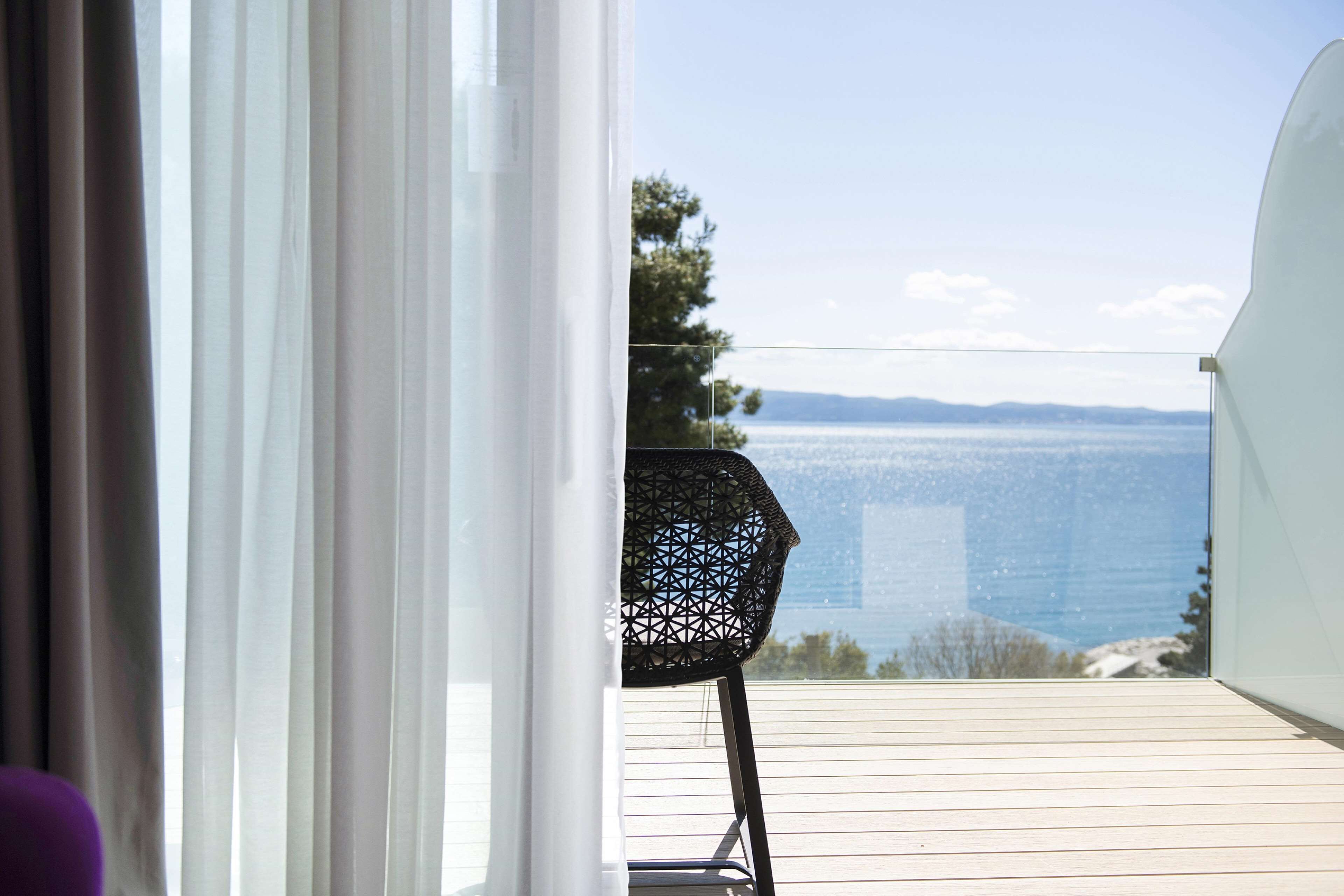 A balcony with a view of the sea and distant mountains.