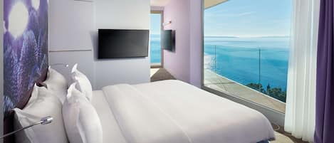 Habitación de hotel con una cama grande, televisión de pantalla plana y balcón con vistas al mar.