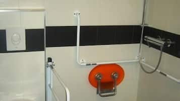 A bathroom with a white toilet, a shower, and a handrail.