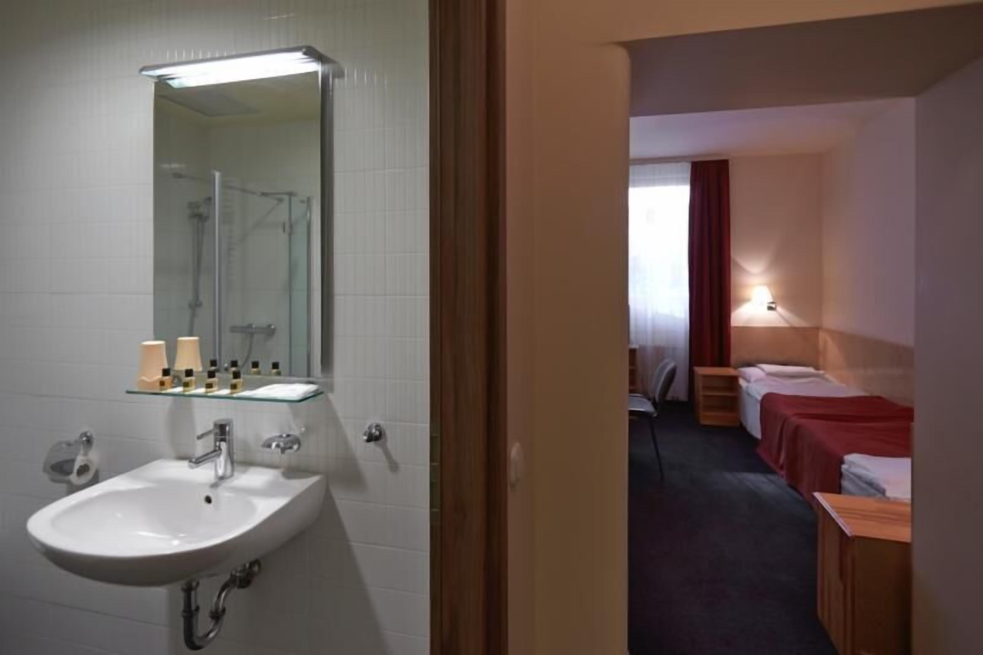 A hotel bathroom with a sink, mirror, and shower.