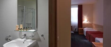 Baño de hotel con lavamanos, espejo y ducha.