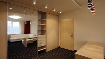 A hotel room with a bed, a desk, a wardrobe, and a small table.