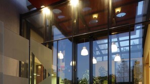 A modern building with a glass facade, outdoor plants, and a staircase leading to the entrance. - Hotel Laterum (Pecs)