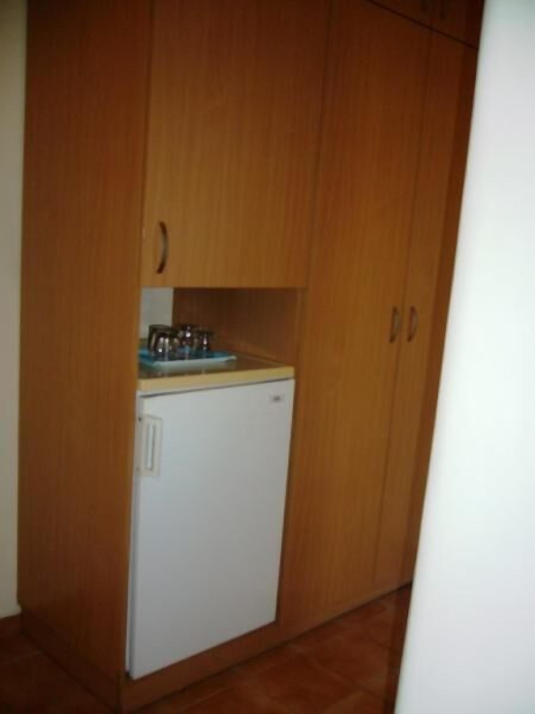 A compact kitchen with wooden cabinets, a white refrigerator, and a small countertop with a sink.