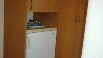 A compact kitchen with wooden cabinets, a white refrigerator, and a small countertop with a sink.