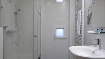 A modern bathroom with a glass-enclosed shower, a white sink, and a toilet.