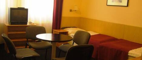 A hotel room with a bed, a desk, a chair, a television, and a picture on the wall.