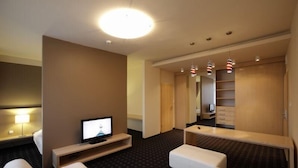 A hotel room with a TV, a desk, a chair, a sofa, and a wardrobe. - Hotel Laterum (Pecs)