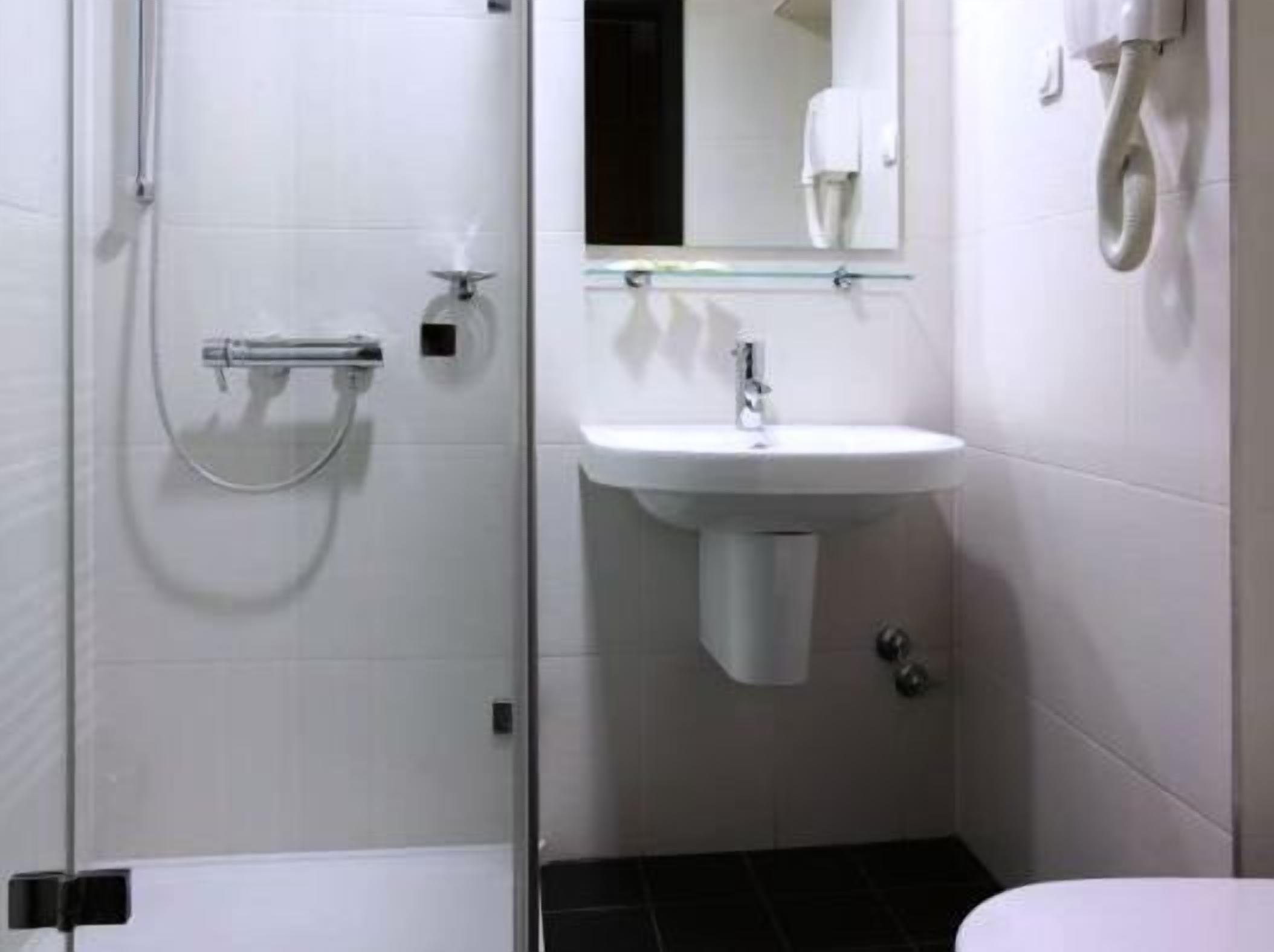 Un baño con ducha, lavabo y espejo.