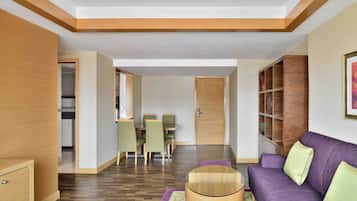 Una sala moderna con un sofá púrpura, una mesa de centro de madera y un comedor con sillas verdes.