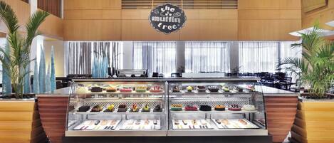 A bakery counter with a variety of baked goods and a sign that reads "The Muffin Tree."