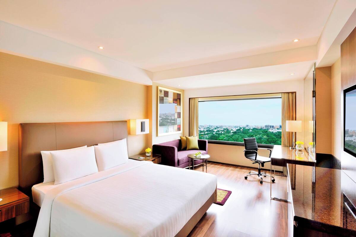 Une chambre d’hôtel avec un grand lit, un bureau, une chaise et une vue sur la ville.