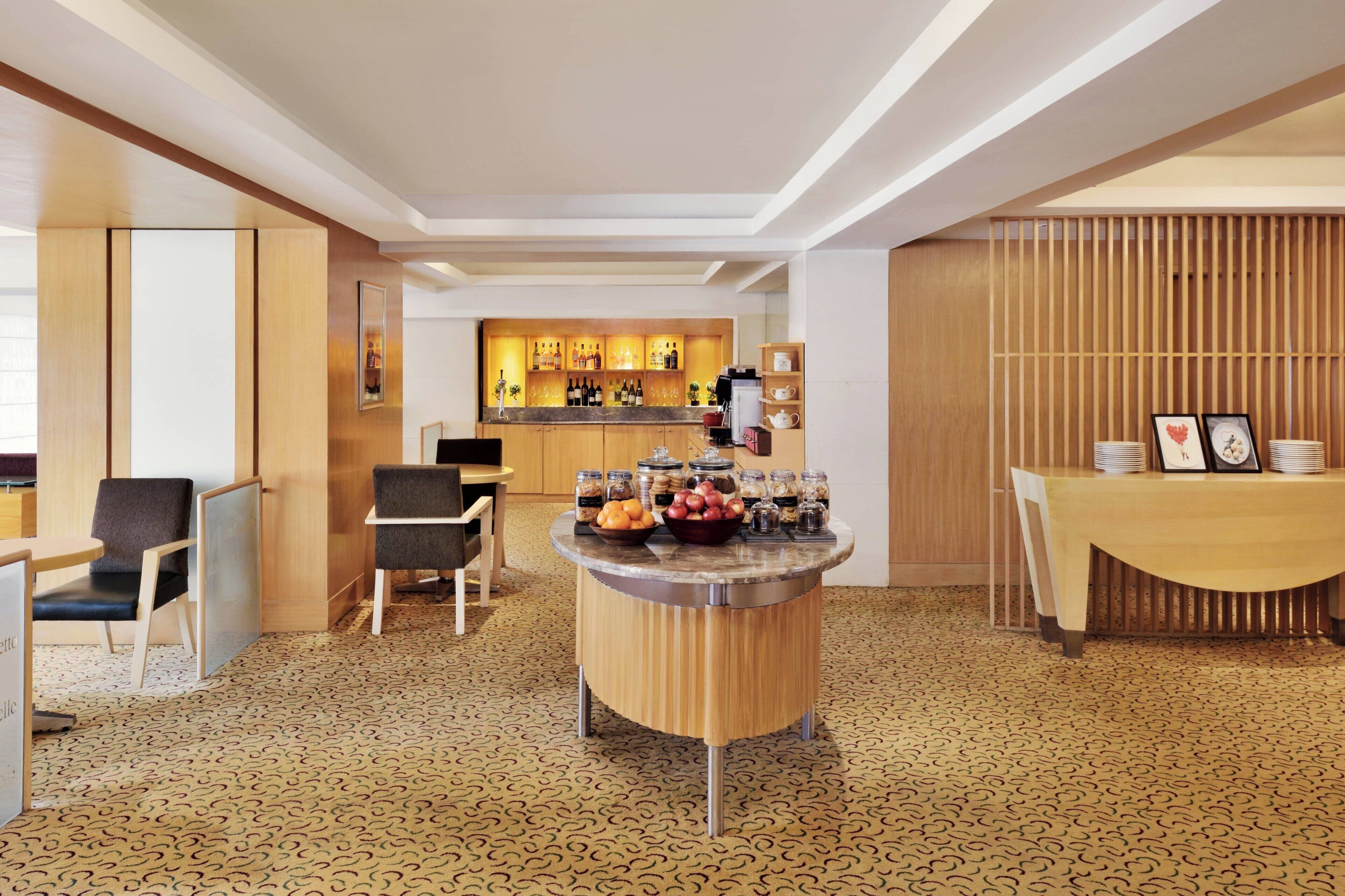 Un moderno vestíbulo de hotel con una barra central, arreglos de asientos y un suelo con diseño.