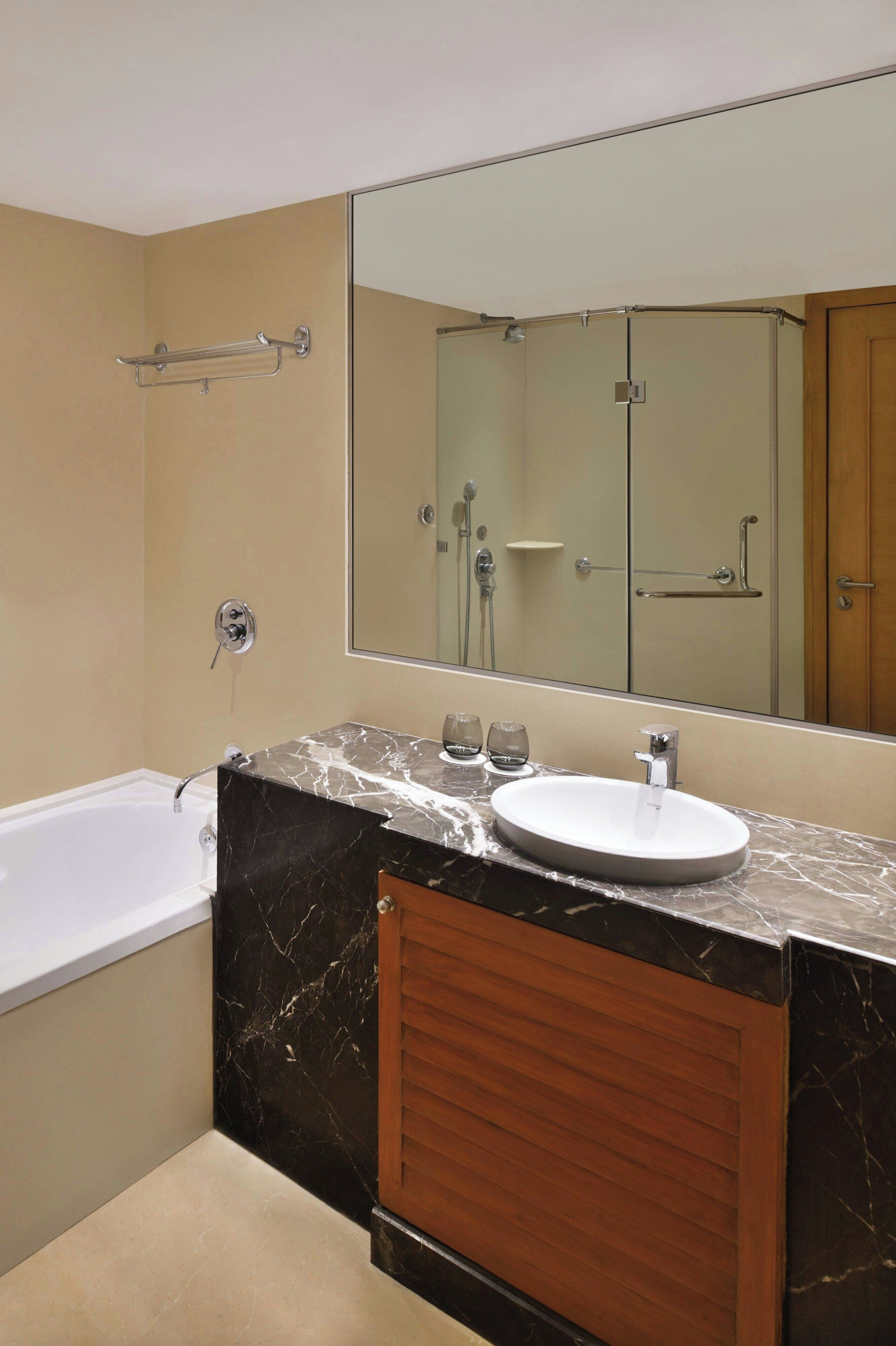Un baño moderno con bañera, lavamanos con encimera de mármol y un espejo grande.
